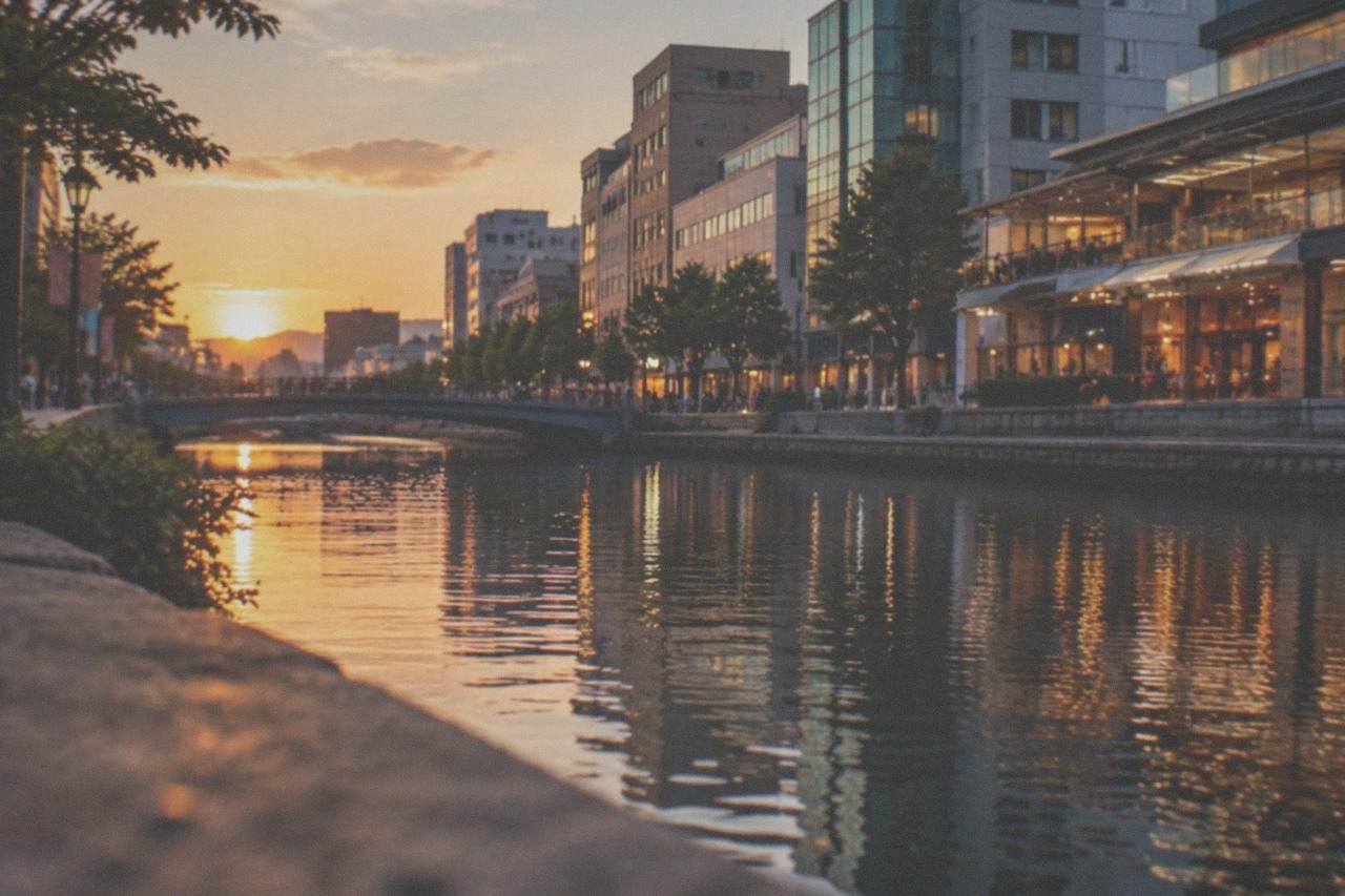 Canal-side shopping complex with illuminated retail terraces reflected in the water at dusk