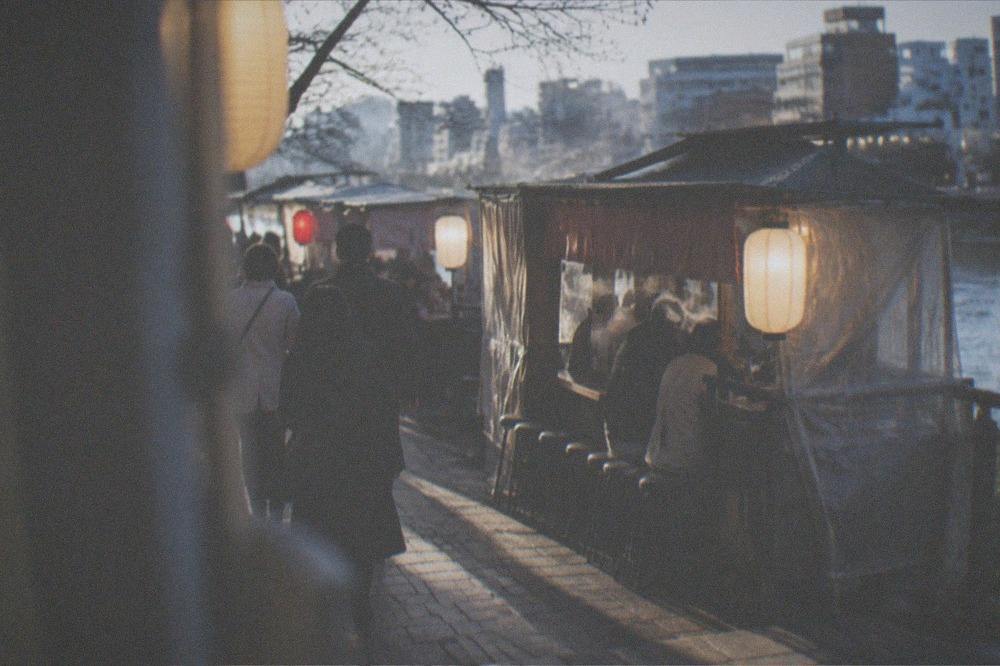 A small group with a guide walking through a lantern-lit food stall district at night