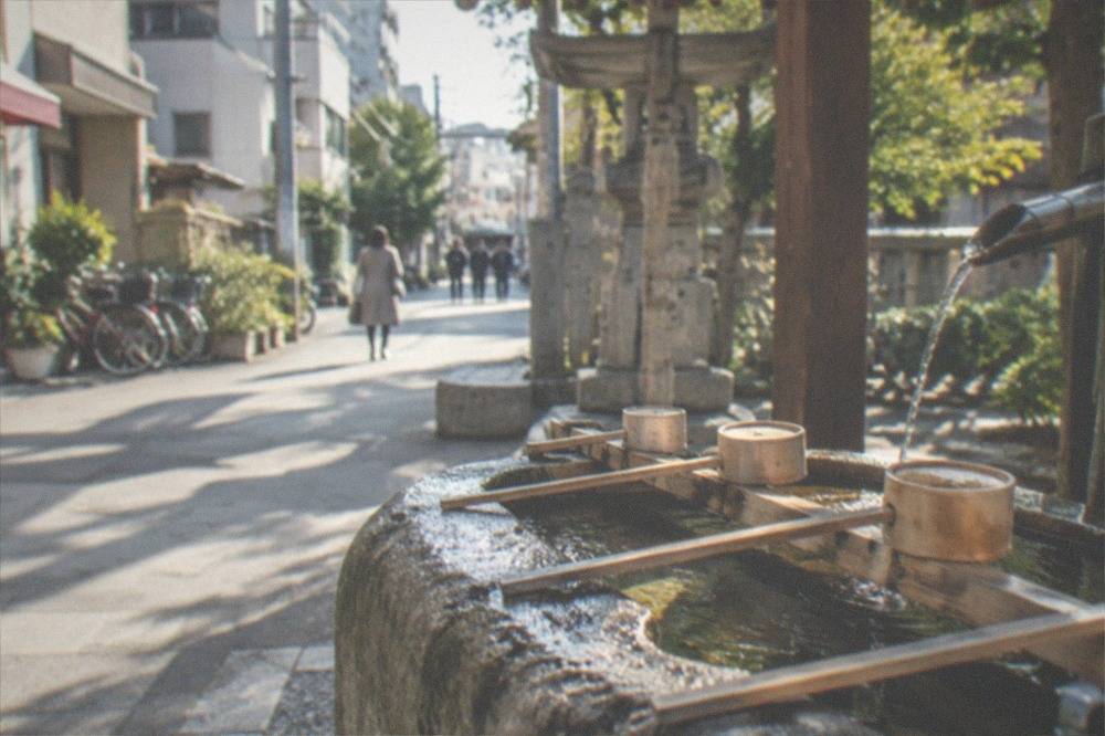 A stone water pavilion with wooden ladles at a shrine entrance