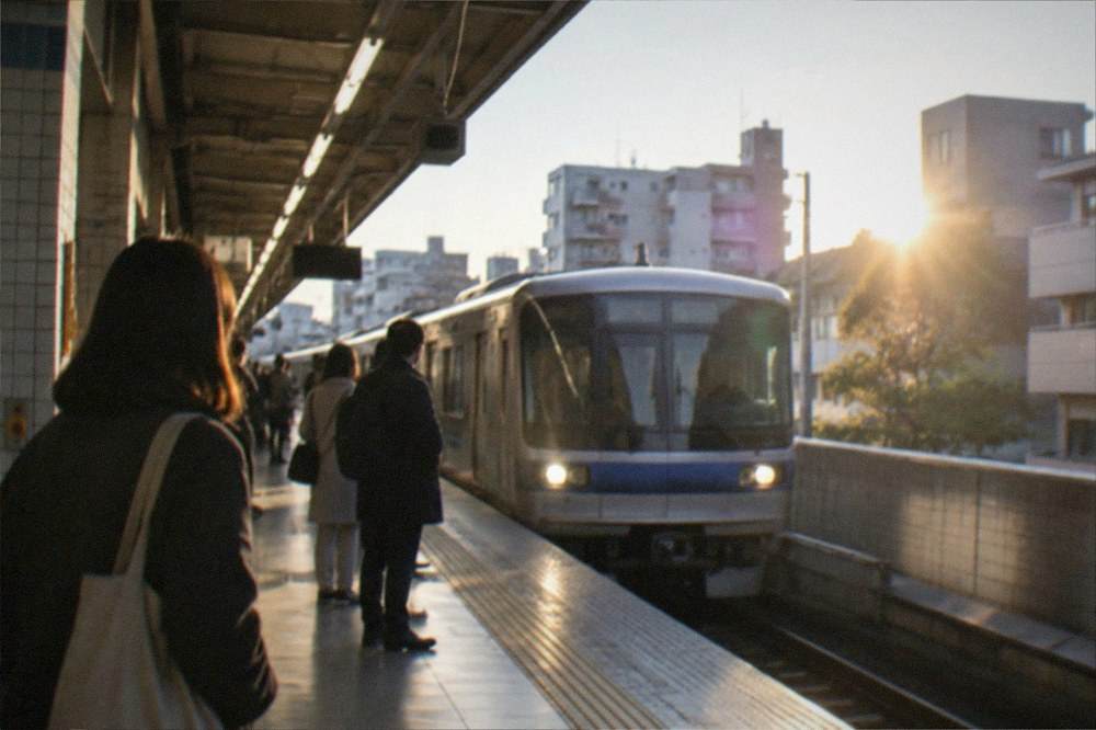 A subway station platform in Fukuoka with a train arriving and passengers waiting