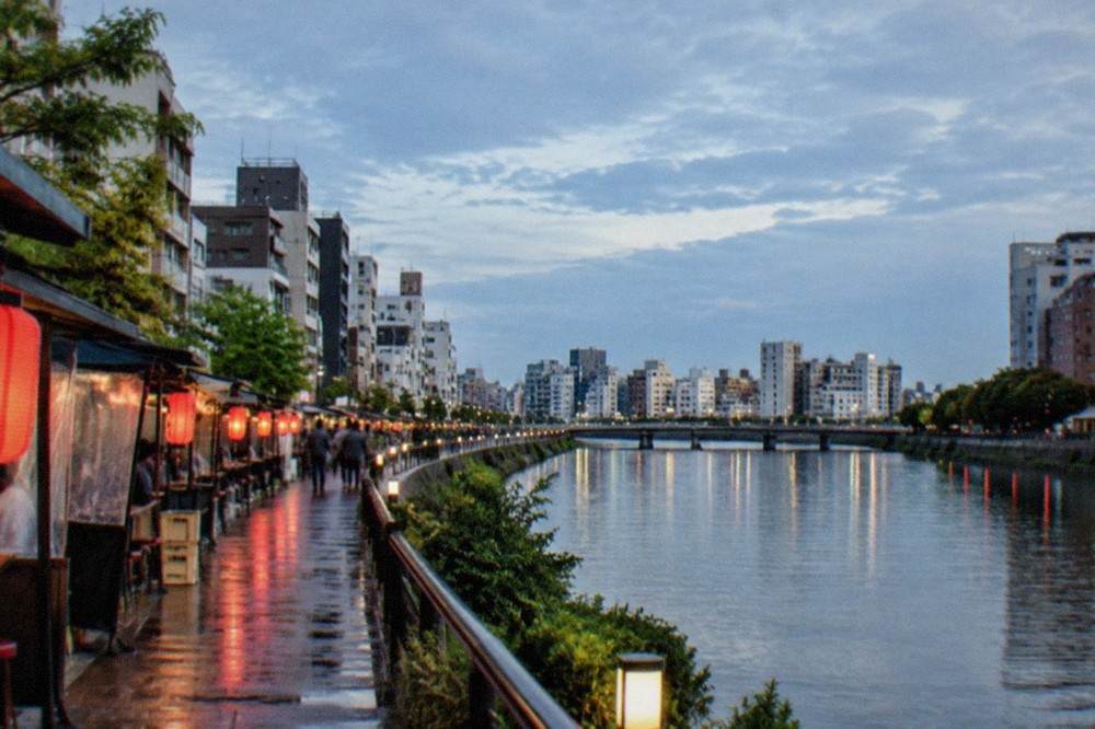 Food stalls with red lanterns glowing along the Naka River in Nakasu at night