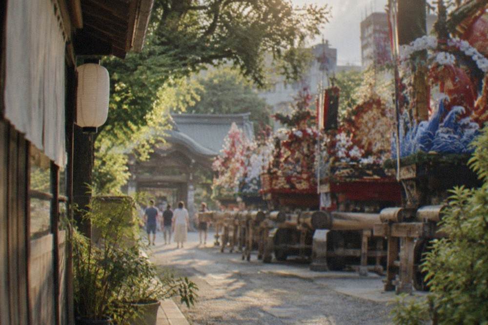 Rows of colourful decorated festival floats lined up inside a shrine courtyard