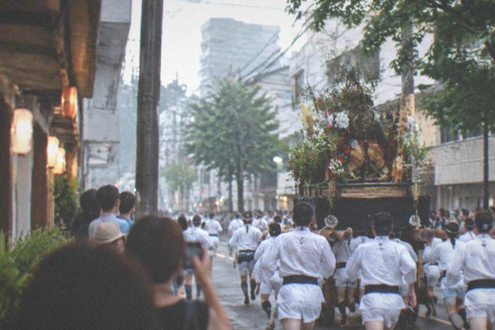 Festival float carried at speed past crowded spectator lines on a city street before dawn