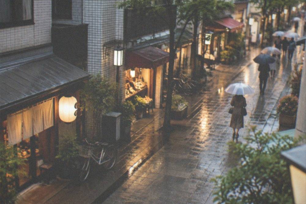A pedestrian shopping street with illuminated shopfronts at night