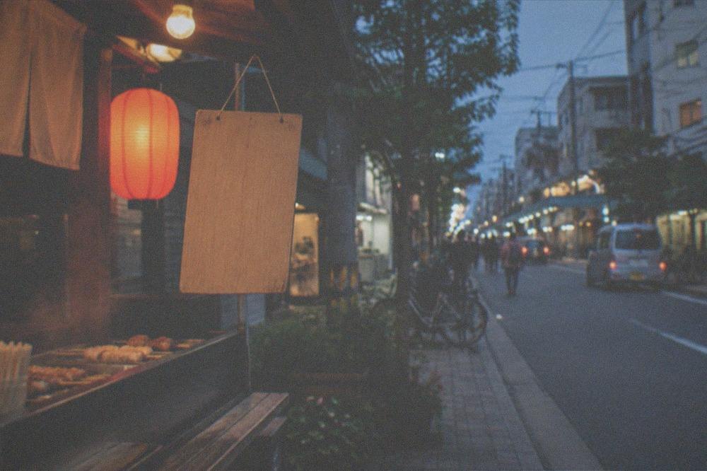 A handwritten price board hanging at the front of a small food stall