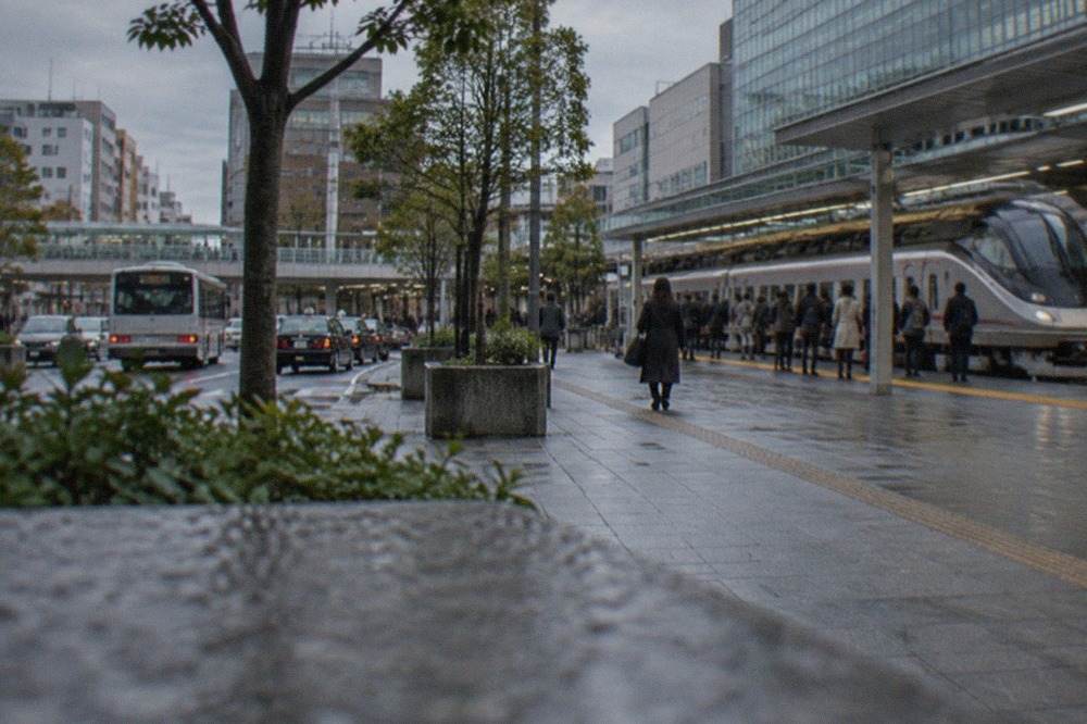 A sleek limited express train at a platform in Fukuoka with passengers waiting behind a yellow safety line