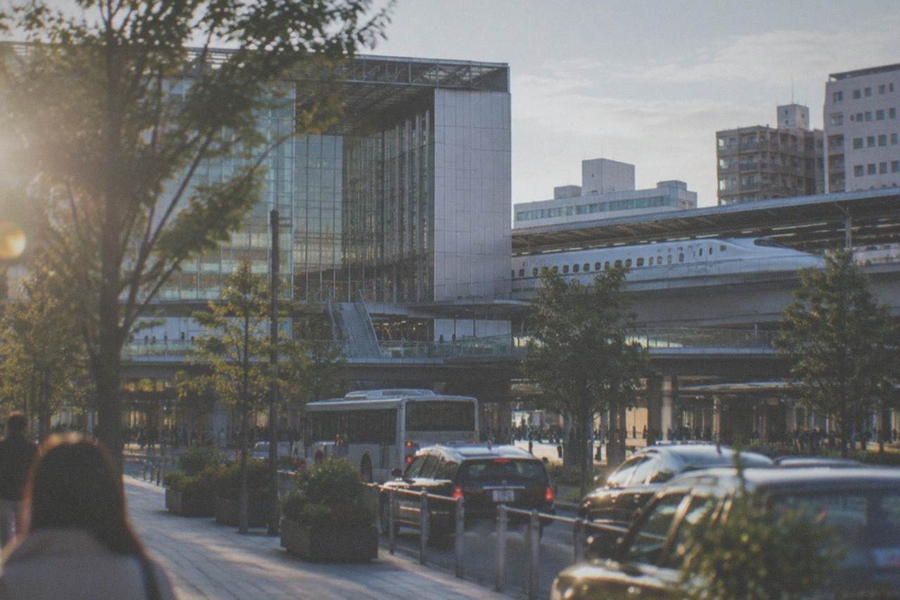 A white shinkansen bullet train waiting at a station platform under a bright sky
