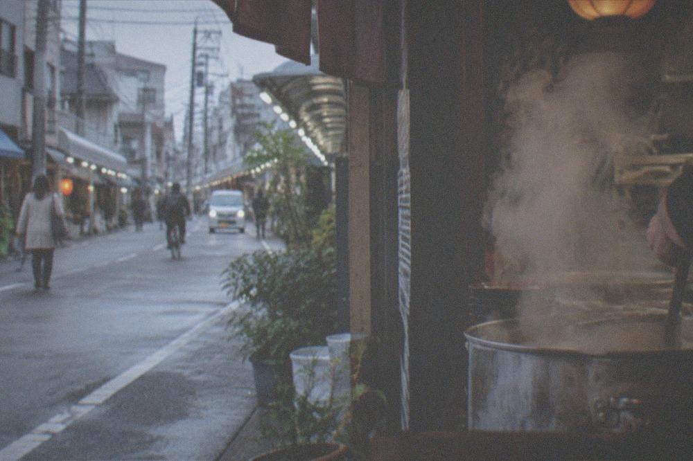 Steam rising from a ramen pot behind a shop counter during evening service