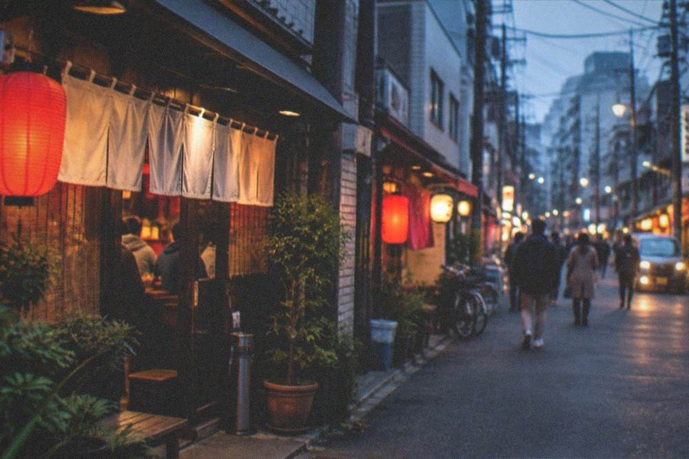 A busy ramen restaurant street with glowing signs and a queue of stools in Fukuoka