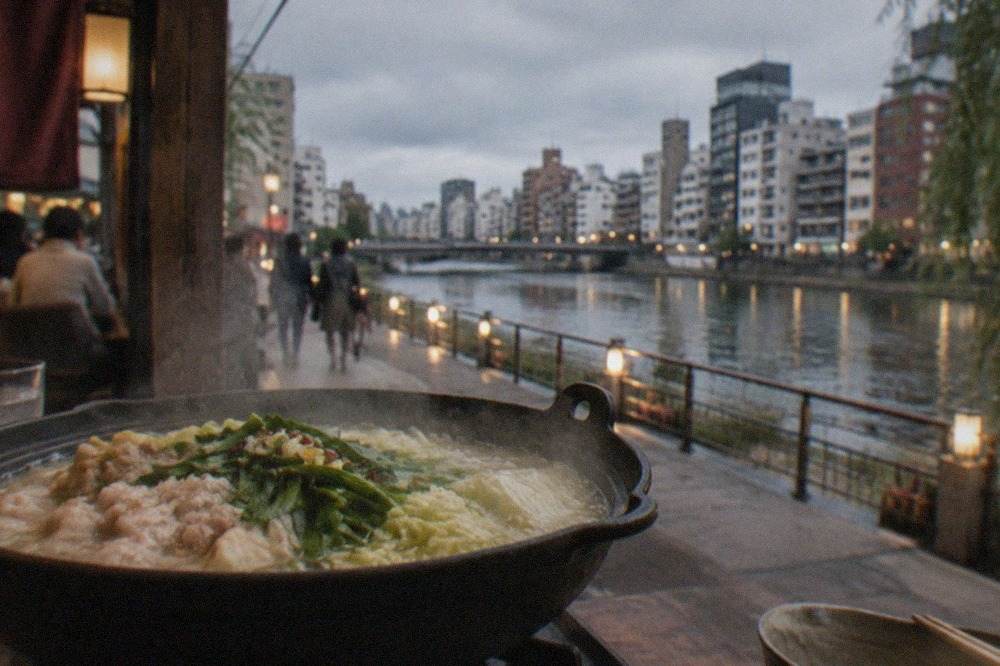 A steaming cast iron hot pot filled with offal, cabbage and broth on a restaurant table