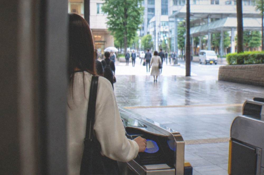 A passenger tapping an IC card on a reader at a station ticket gate in Fukuoka