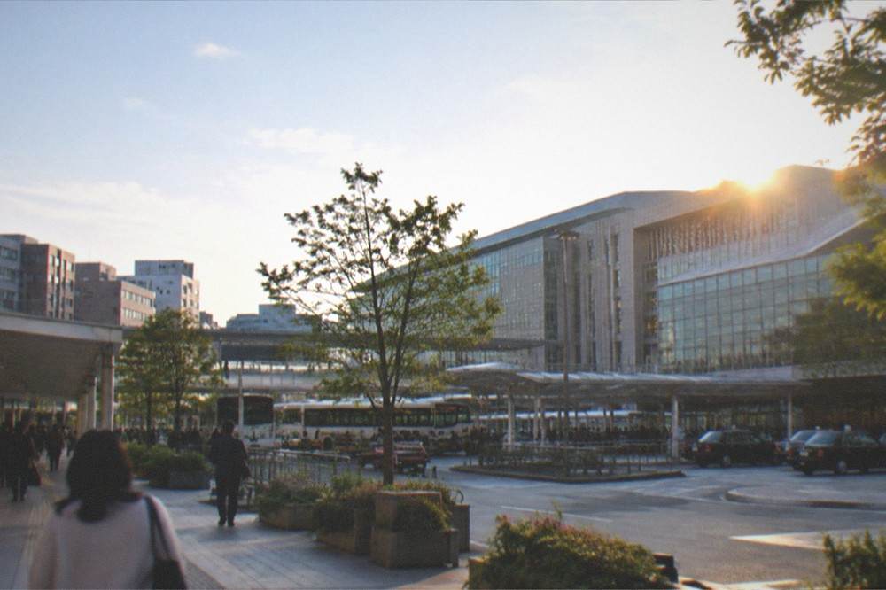 Modern station concourse with departure boards and travellers walking beneath them