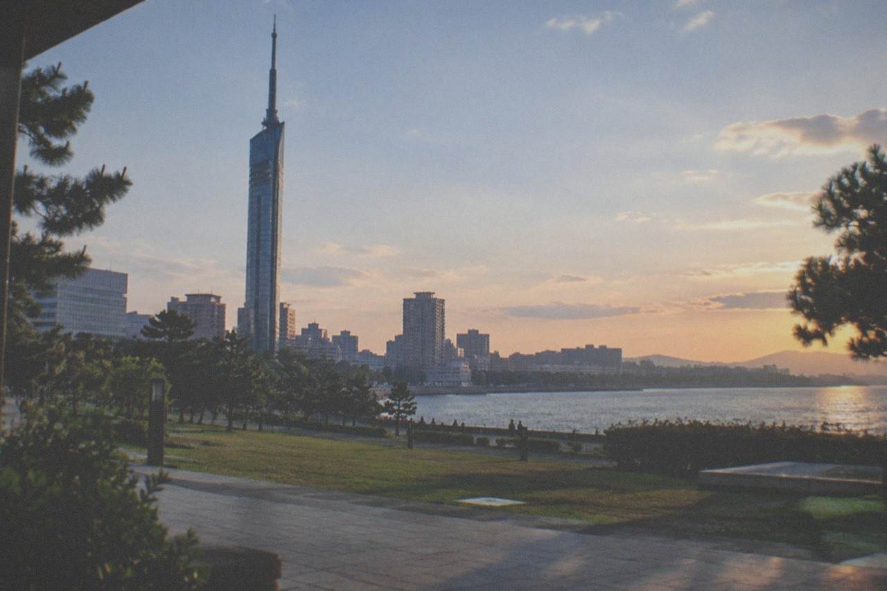 A wide view of Fukuoka city skyline with the Fukuoka Tower silhouette against Hakata Bay at dusk