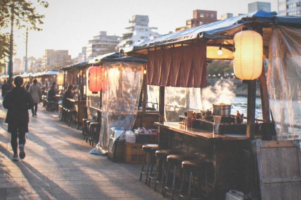 A food stall opening for the evening with a handwritten menu board displayed at the counter