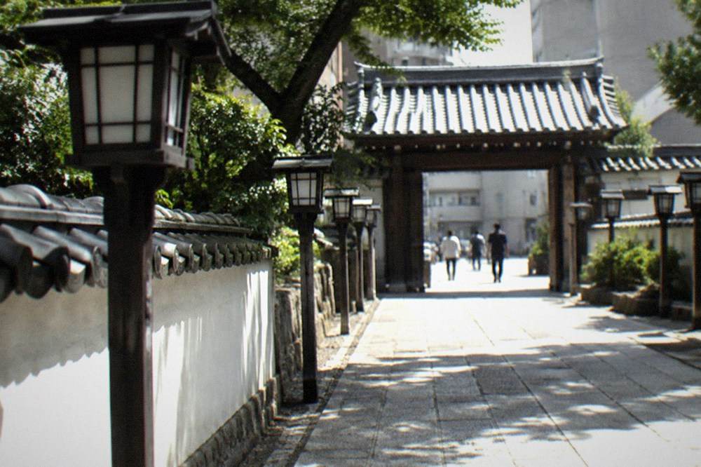 Lantern-lined stone path leading to a wooden temple gate in Hakata old town