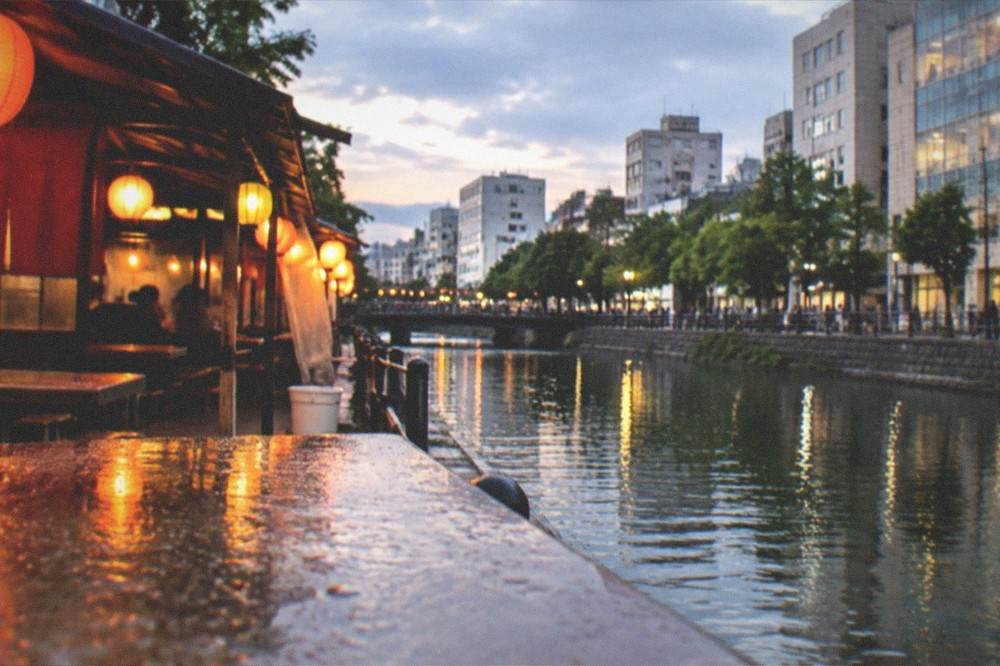 Evening food stall with lanterns glowing beside a canal in central Fukuoka