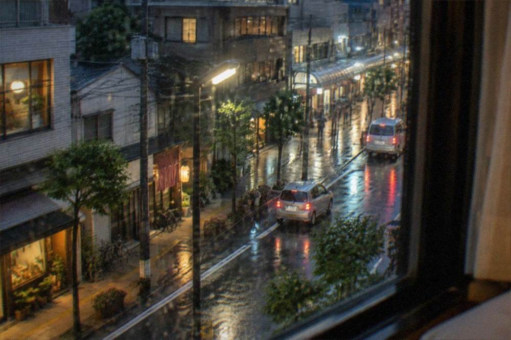 Steam rising from vents beside a boardwalk at a hot spring town in light rain