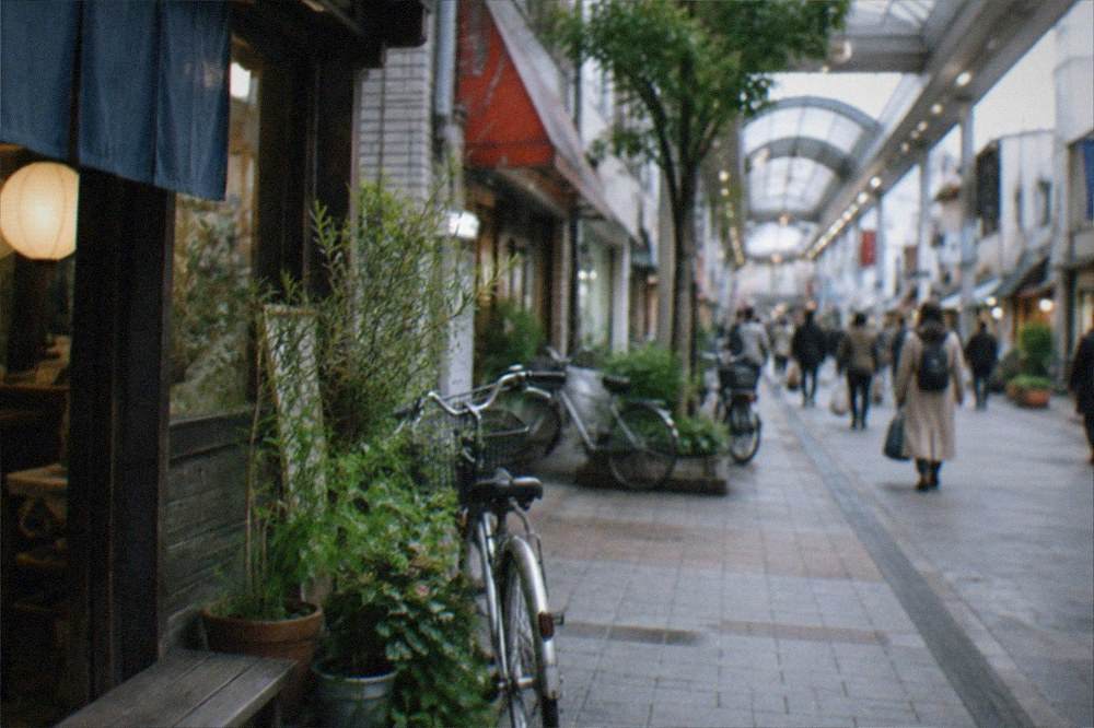 Busy covered shopping street with illuminated signs in a Japanese city district at dusk
