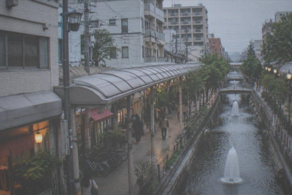 Indoor shopping canal running between buildings with fountains and covered walkways